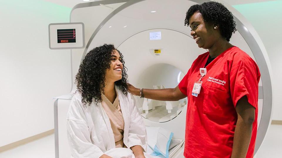 A nurse and a patient who is sitting next to MRI